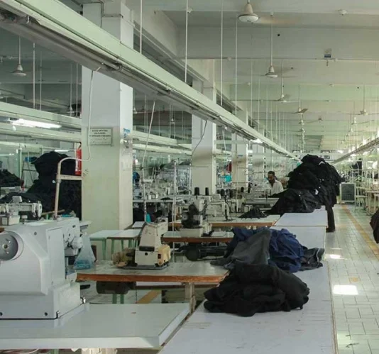 Prague Sports skilled garment workers operating industrial sewing machines, handcrafting premium custom sportswear on the production floor for international export.